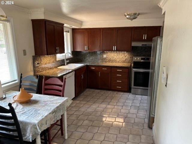 kitchen featuring dark stone countertops, backsplash, stainless steel appliances, ornamental molding, and sink