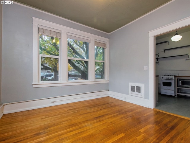 spare room featuring dark hardwood / wood-style flooring, crown molding, and plenty of natural light