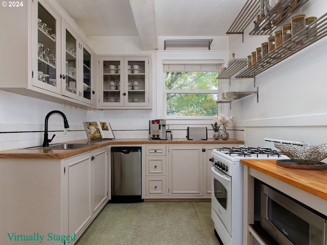 kitchen featuring backsplash, appliances with stainless steel finishes, sink, white cabinets, and wood counters