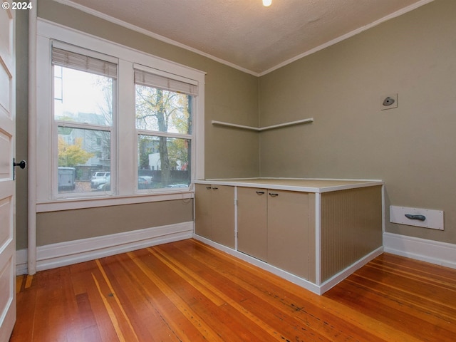 spare room featuring crown molding, light hardwood / wood-style floors, and a textured ceiling