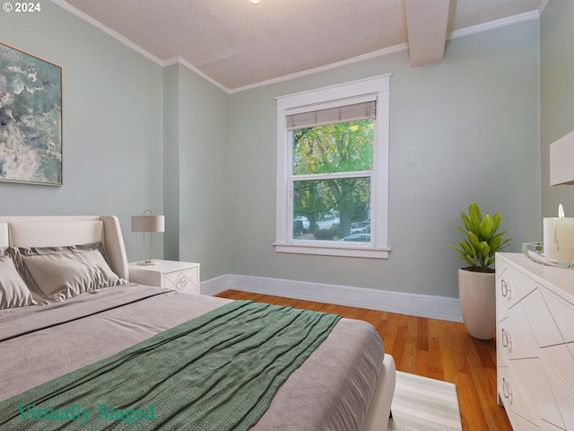 bedroom featuring a textured ceiling, ornamental molding, and light hardwood / wood-style flooring