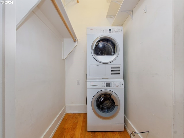 laundry room with stacked washer / dryer and light hardwood / wood-style floors