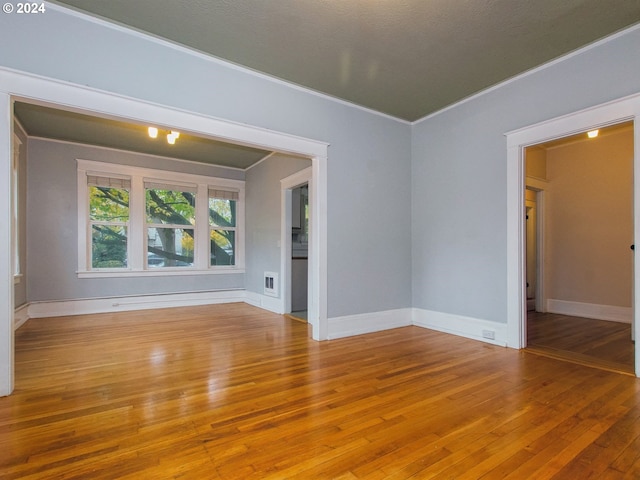 unfurnished room with light wood-type flooring and ornamental molding