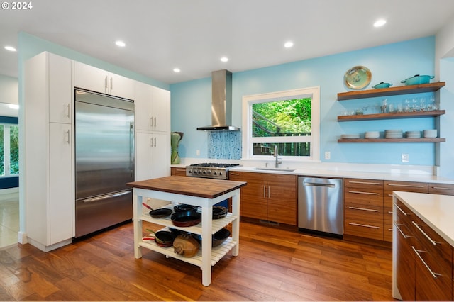 kitchen with stainless steel appliances, wall chimney exhaust hood, white cabinetry, and dark hardwood / wood-style flooring