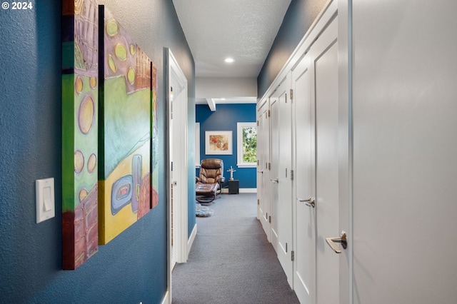 corridor with a textured ceiling and carpet floors