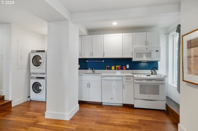 kitchen with a wealth of natural light, stacked washing maching and dryer, light wood-type flooring, and white appliances