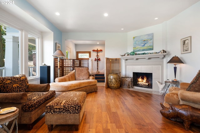 living room with a tile fireplace and light hardwood / wood-style flooring