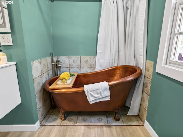 bathroom featuring a bathtub, tile walls, and hardwood / wood-style floors