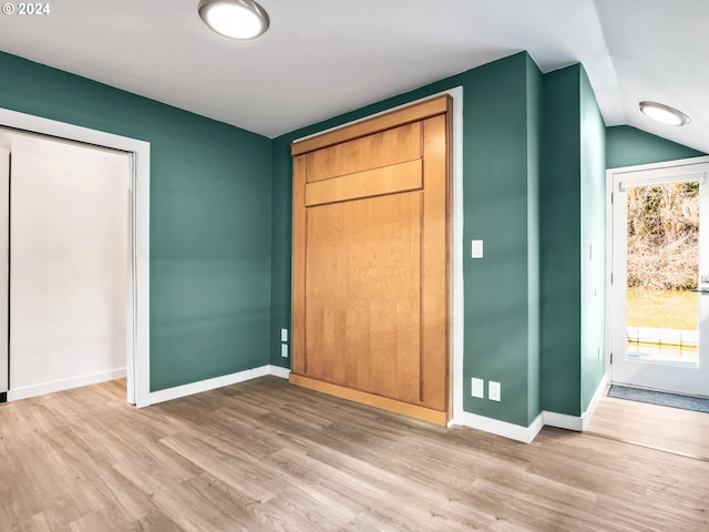 unfurnished bedroom with lofted ceiling and hardwood / wood-style floors