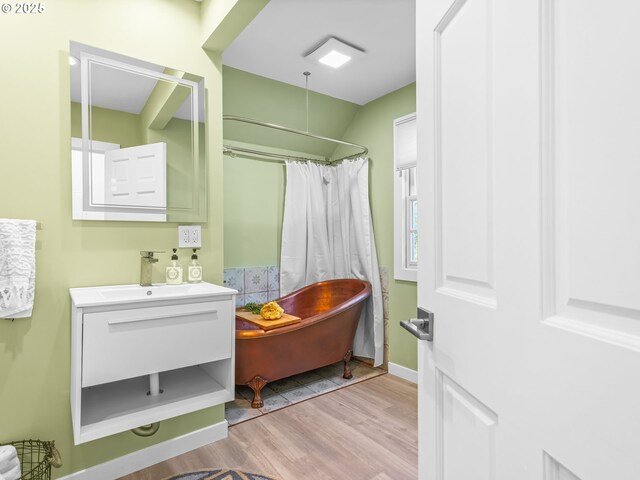 14581 NW Larson Rd Unit 7, Portland, OR 97231 - bathroom with curtained shower, wood finished floors, vanity, baseboards, and a freestanding tub