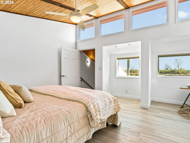 bedroom featuring wood ceiling, a towering ceiling, light wood-type flooring, and ceiling fan