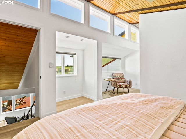 bedroom featuring light hardwood / wood-style floors, wooden ceiling, and a high ceiling