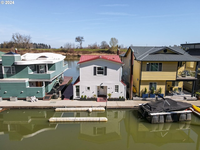 back of property with a water view and a patio area