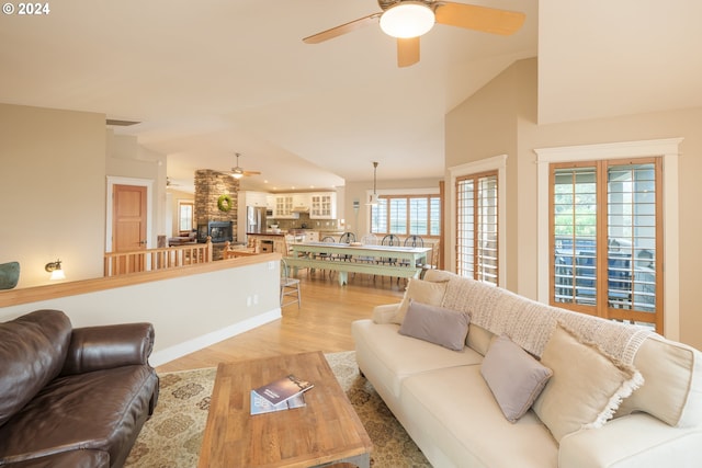 living room featuring ceiling fan, light wood-type flooring, and vaulted ceiling