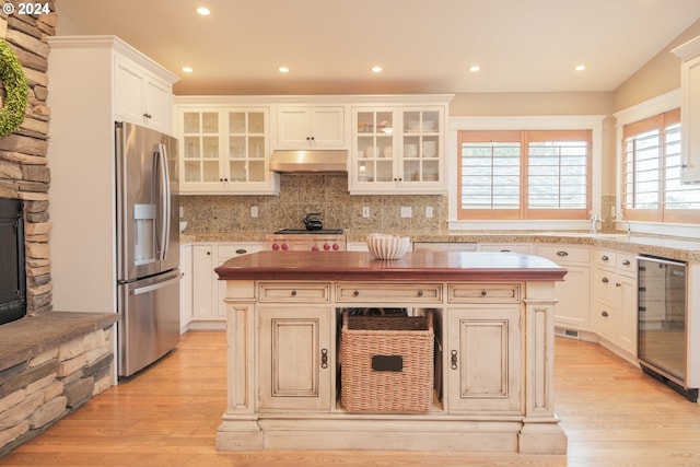 kitchen with a center island, black gas stovetop, wine cooler, and stainless steel refrigerator with ice dispenser