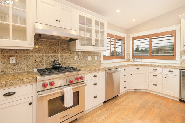 kitchen featuring stainless steel appliances, lofted ceiling, backsplash, white cabinetry, and light hardwood / wood-style flooring