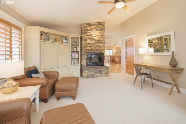 living room with ceiling fan, a stone fireplace, light carpet, and lofted ceiling