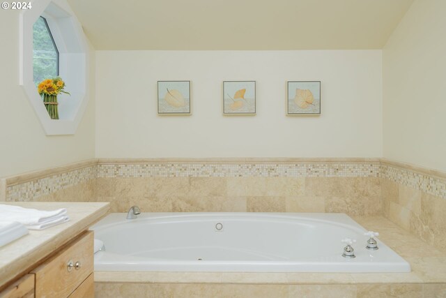 bathroom featuring tiled bath and vanity