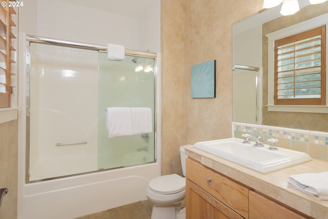 full bathroom with tasteful backsplash, shower / bath combination with glass door, vanity, tile patterned floors, and toilet