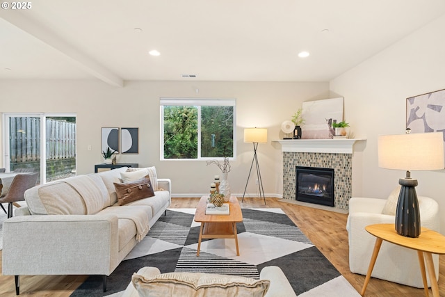 living room featuring beam ceiling, light hardwood / wood-style flooring, plenty of natural light, and a fireplace