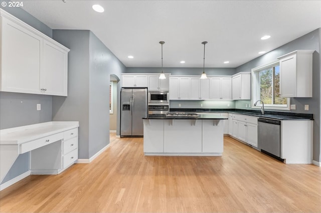 kitchen featuring hanging light fixtures, stainless steel appliances, a kitchen island, light hardwood / wood-style flooring, and white cabinets