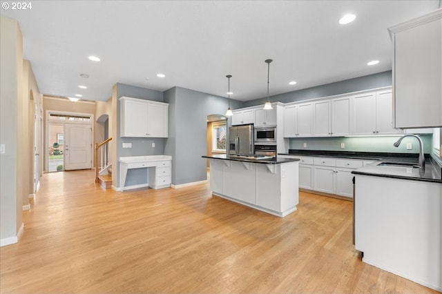 kitchen with a center island, sink, stainless steel appliances, light hardwood / wood-style floors, and white cabinets