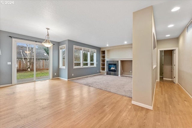 unfurnished living room with a tile fireplace and light hardwood / wood-style flooring