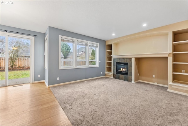 unfurnished living room with a tile fireplace, hardwood / wood-style floors, and a healthy amount of sunlight