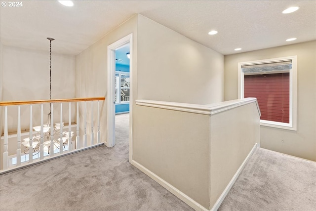 hall featuring plenty of natural light, carpet floors, and a textured ceiling