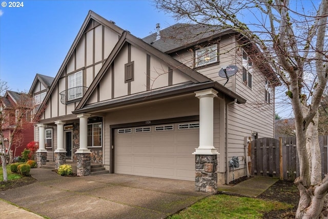 english style home featuring covered porch, a garage, and a balcony