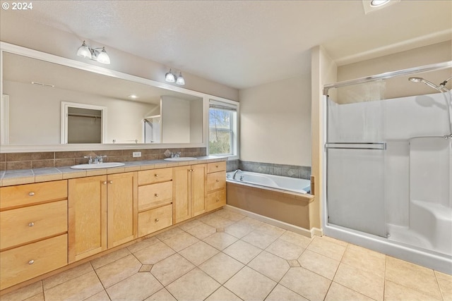 bathroom featuring tile patterned flooring, shower with separate bathtub, vanity, and a textured ceiling