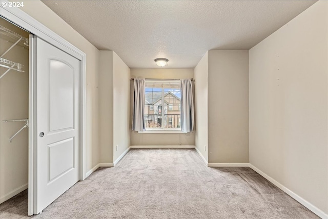 interior space with light colored carpet, a textured ceiling, and a closet