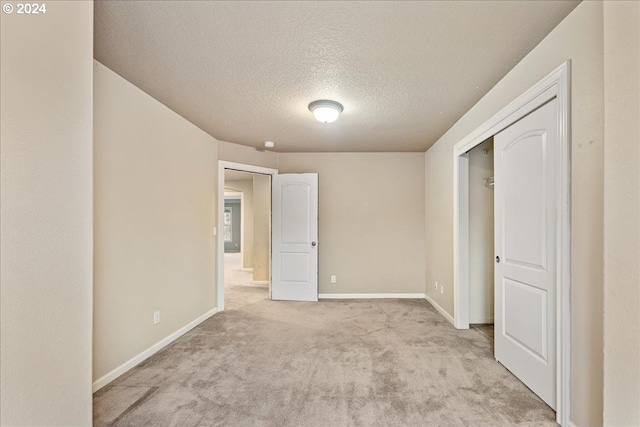 unfurnished bedroom with light carpet, a textured ceiling, and a closet