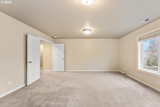 spare room with a textured ceiling and light colored carpet