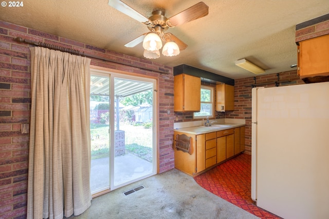 kitchen featuring white fridge, brick wall, ceiling fan, and sink