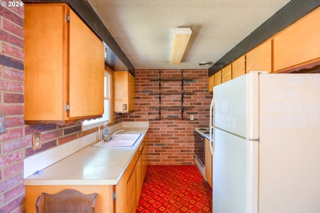 kitchen with brick wall, white appliances, a textured ceiling, and sink