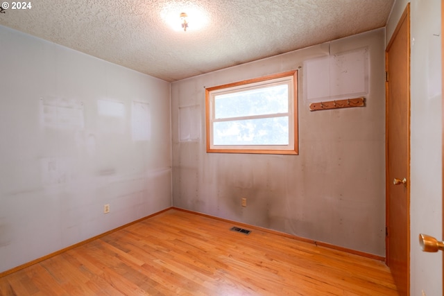 empty room featuring a textured ceiling and light hardwood / wood-style flooring