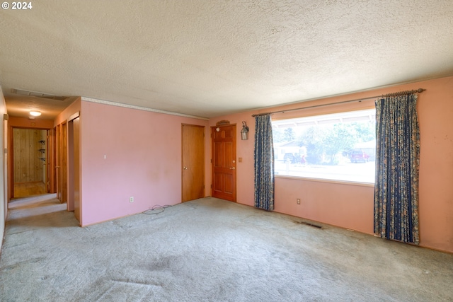 empty room with a textured ceiling and carpet flooring