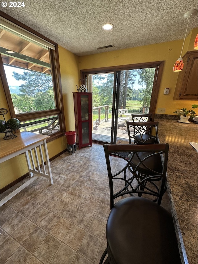 tiled dining area featuring plenty of natural light and a textured ceiling