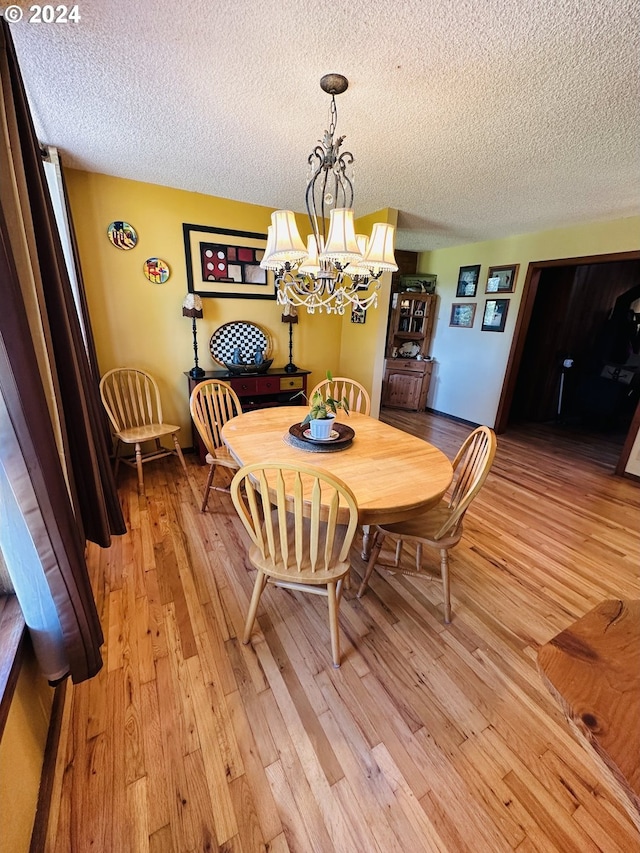 dining room featuring light wood-type flooring, a textured ceiling, and a chandelier