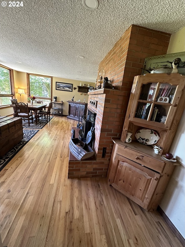 living room featuring a textured ceiling, a brick fireplace, hardwood / wood-style floors, and brick wall