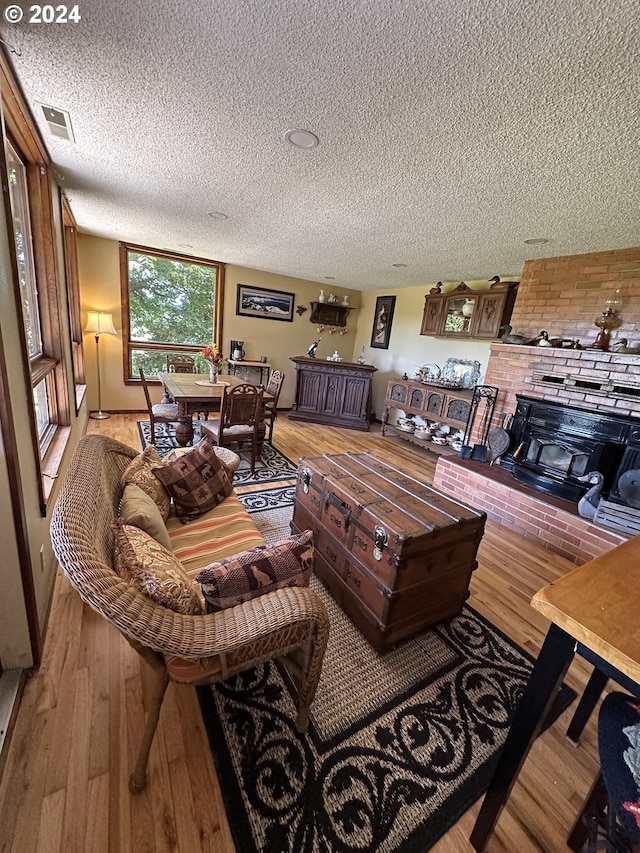 living room with a textured ceiling, brick wall, and wood-type flooring