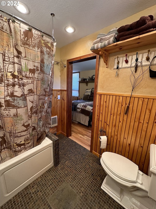 bathroom featuring tile patterned floors, a textured ceiling, shower / bathtub combination with curtain, and toilet