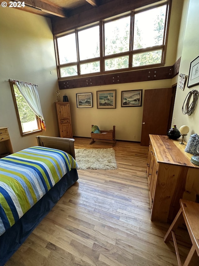 bedroom with multiple windows, beamed ceiling, and hardwood / wood-style floors