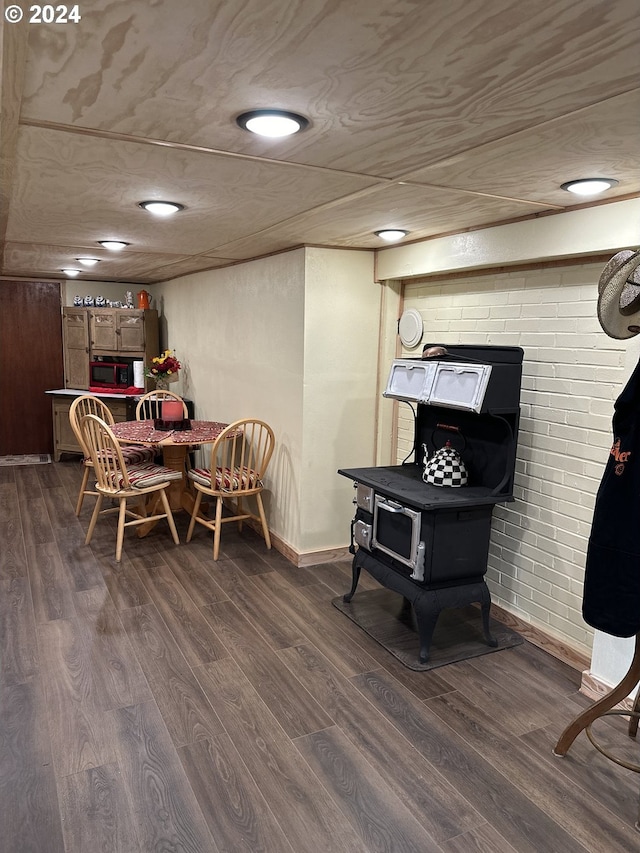 living area with a wood stove, brick wall, and wood-type flooring