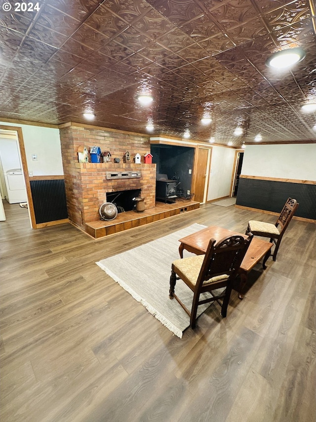 living room with brick wall, crown molding, wood-type flooring, and a brick fireplace