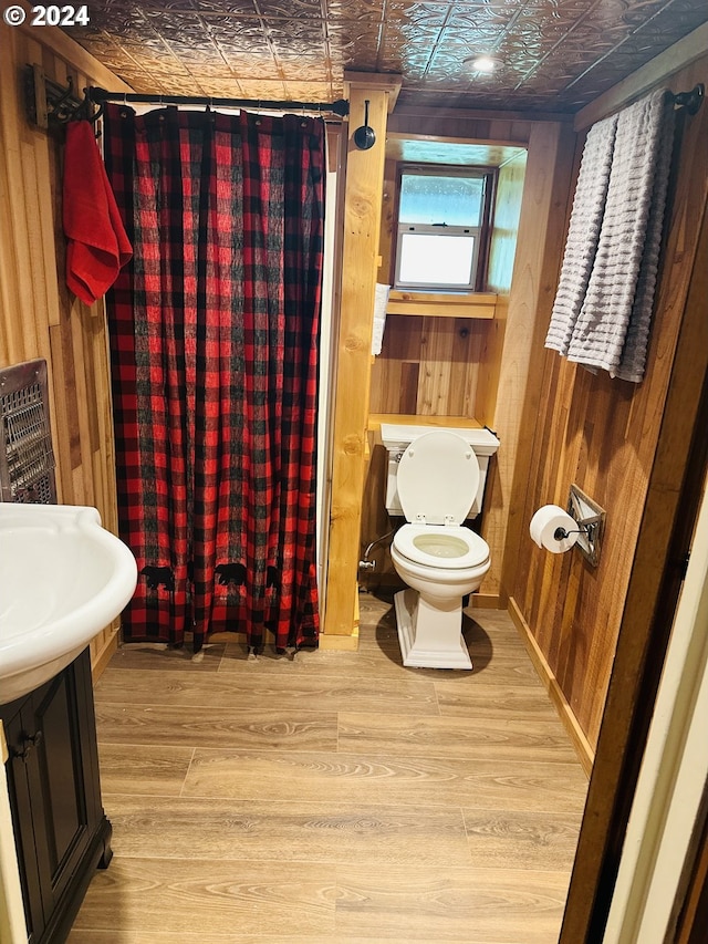 bathroom with hardwood / wood-style floors, a shower with shower curtain, toilet, and wooden walls