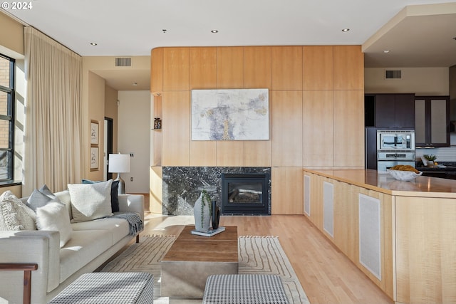 living room featuring a premium fireplace and light hardwood / wood-style flooring