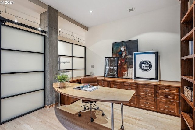 office area with rail lighting and light hardwood / wood-style floors