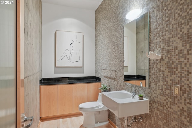 bathroom featuring tasteful backsplash, sink, tile walls, hardwood / wood-style floors, and toilet